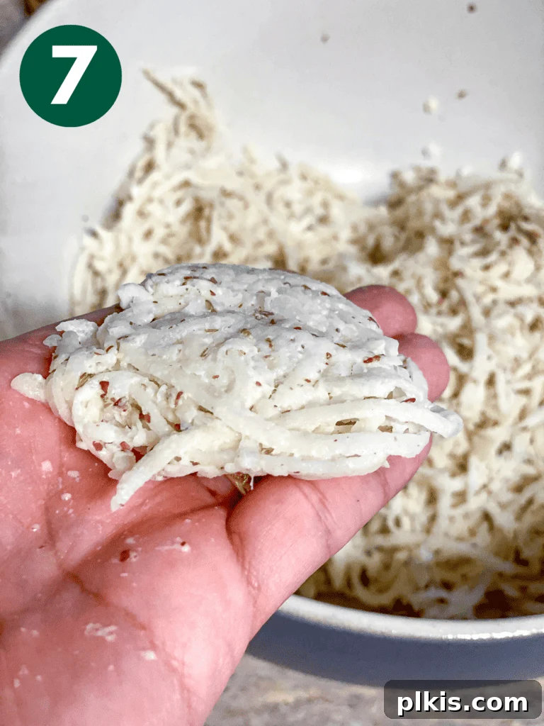 Crispy Vegan Potato Latkes 8 Process shot illustrating hands gently shaping the vegan potato latke mixture into a flat patty before cooking.