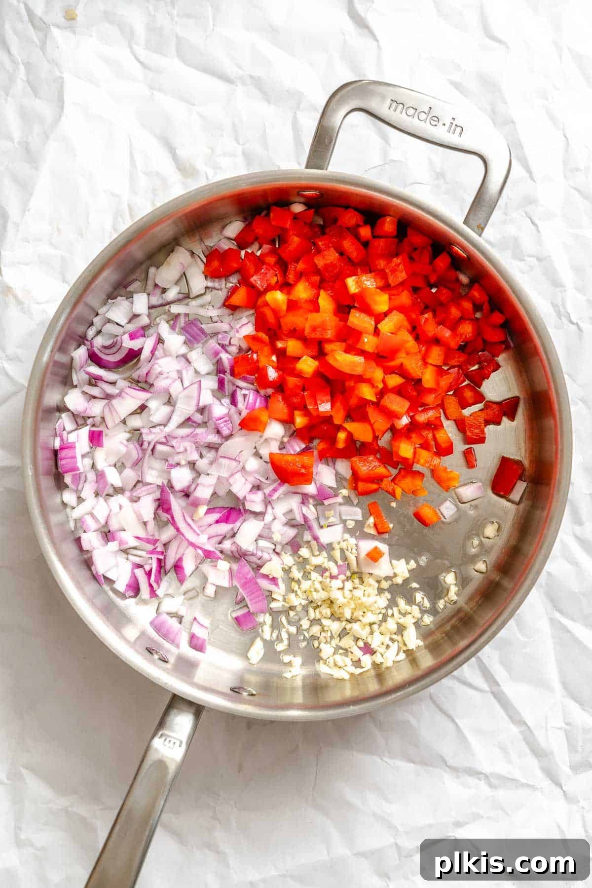 Process shot showing diced onions, garlic, and bell pepper cooking in a large saucepan, creating an aromatic base for the curry soup.