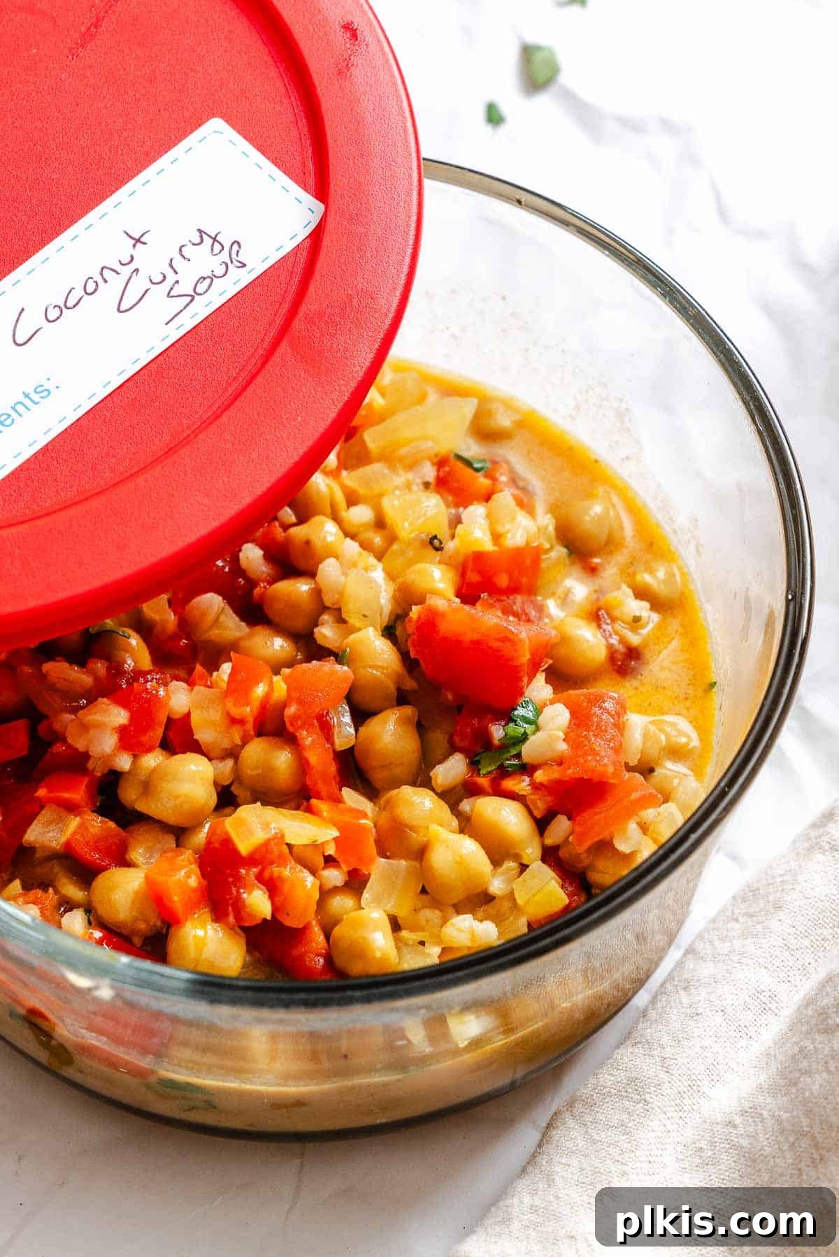 Completed Coconut Chickpea Curry Soup stored in a transparent meal prep container, ready for refrigeration or freezing.