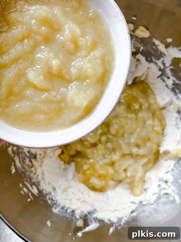 Hearty Vegan Fruit Loaf 5 Process shot illustrating applesauce being added to the creamed butter and sugar mixture, ready for the next mixing stage.