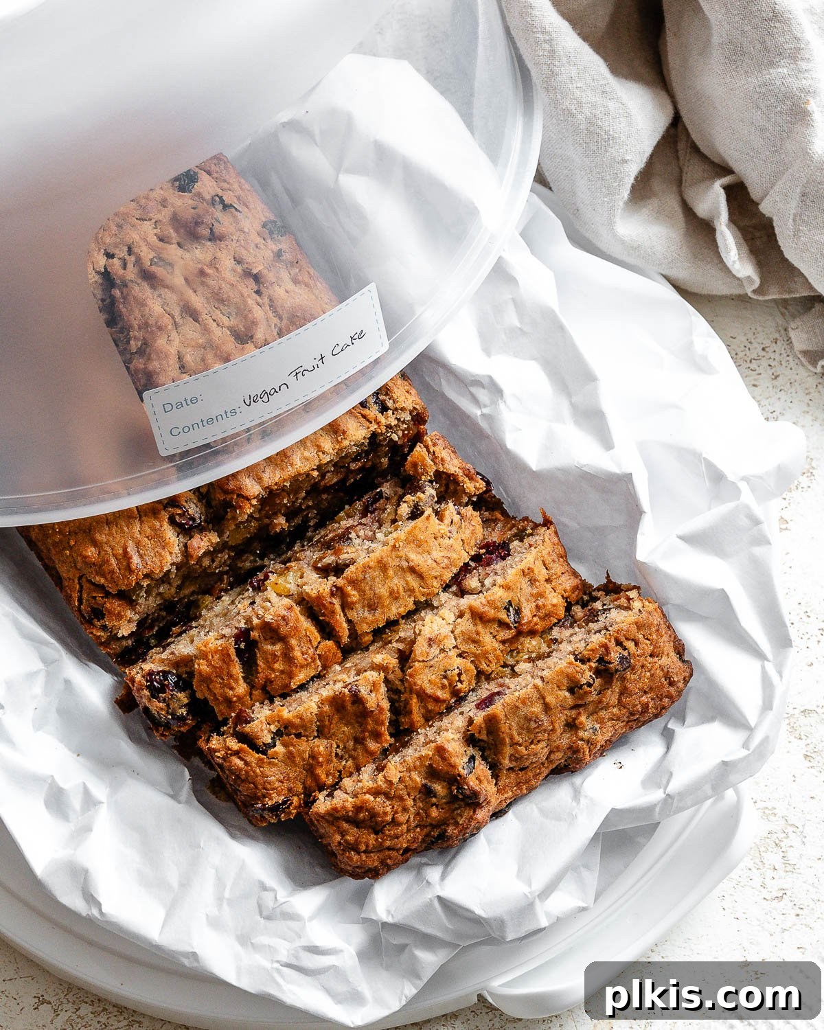 A beautifully presented, whole Vegan Fruit Cake [Fruit Loaf] on a white surface, garnished and ready to be served or stored.