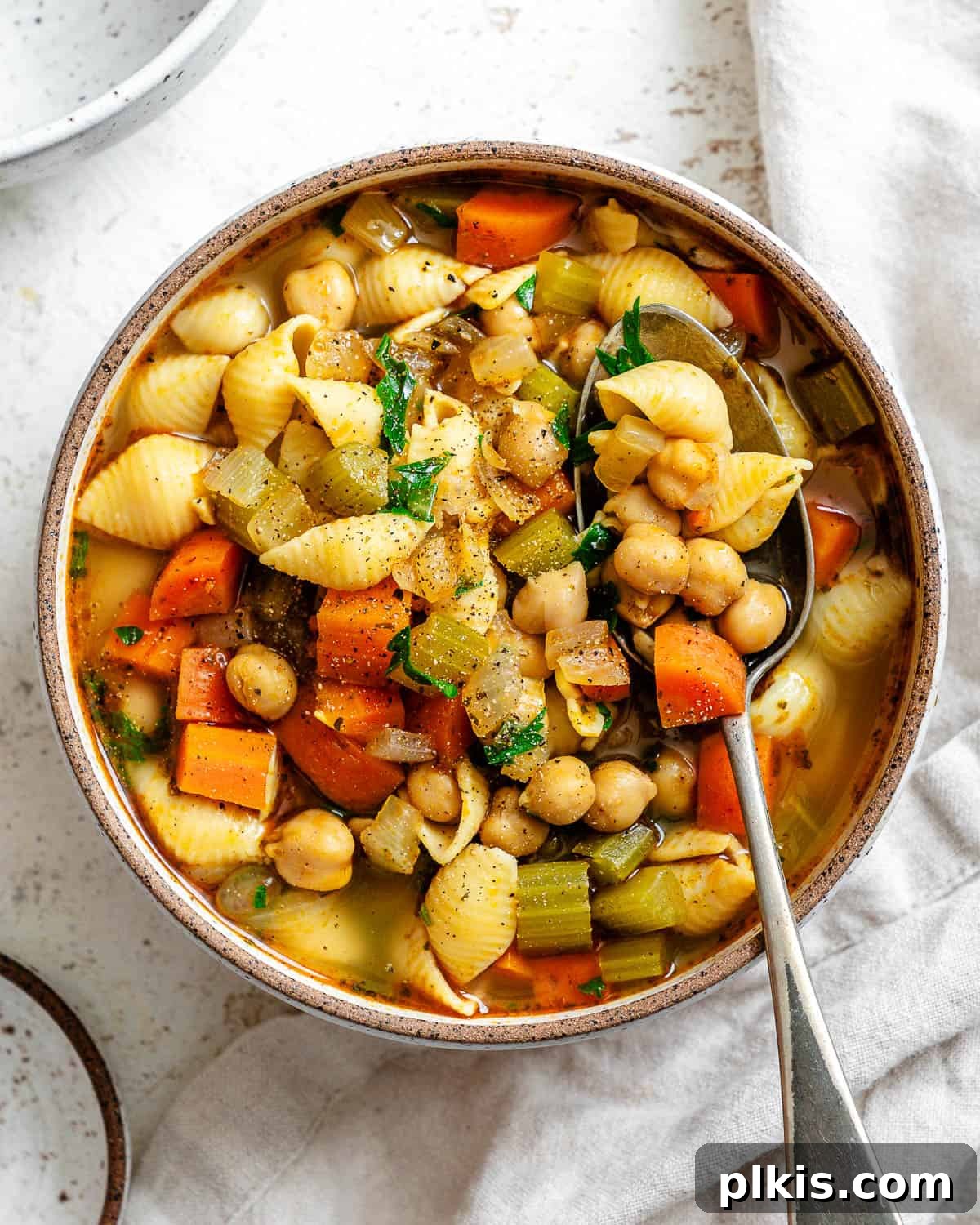 Comforting Vegan Chickpea Noodle Soup 2 Two bowls of Vegan Chickpea Noodle Soup, a comforting plant-based meal ready to be enjoyed, served on a white surface.
