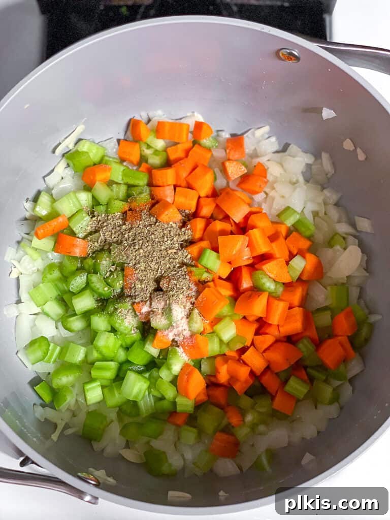 Comforting Vegan Chickpea Noodle Soup 4 Close-up process shot showing diced onions, carrots, and celery sautéing in a large pot on the stovetop.