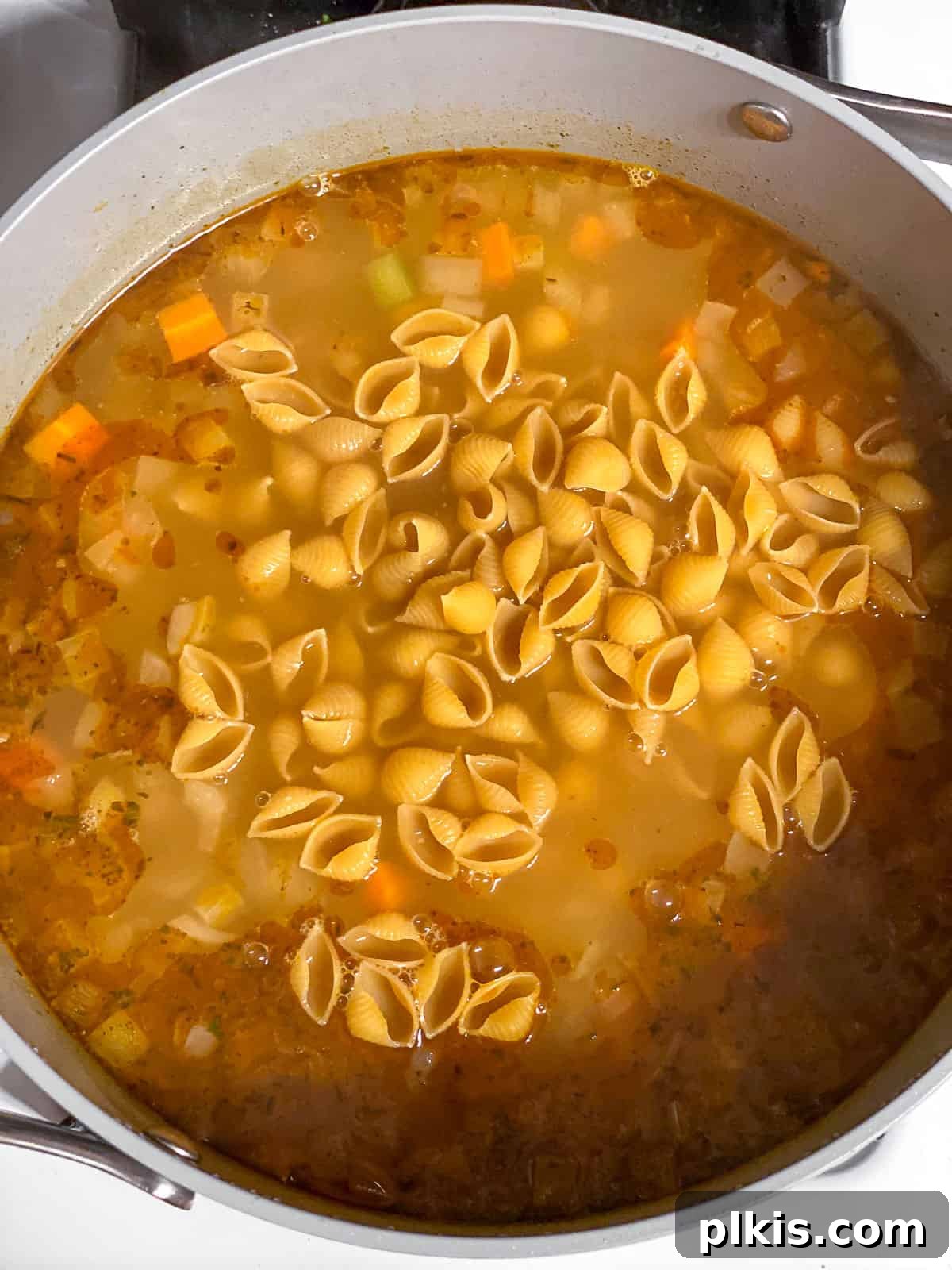 Comforting Vegan Chickpea Noodle Soup 6 Process shot of dry pasta being added to the simmering chickpea noodle soup in a large pot.