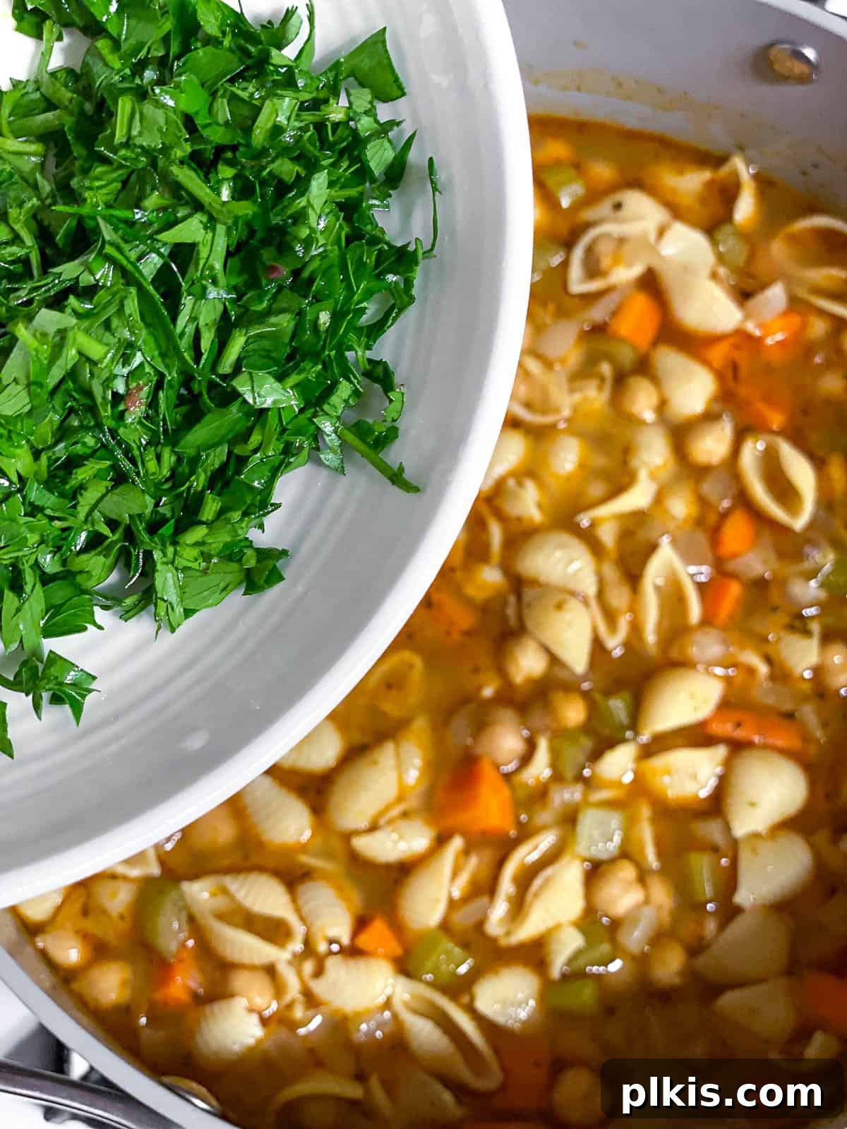 Comforting Vegan Chickpea Noodle Soup 7 Process shot of fresh parsley and lemon juice being added to the finished chickpea noodle soup for garnish and flavor.