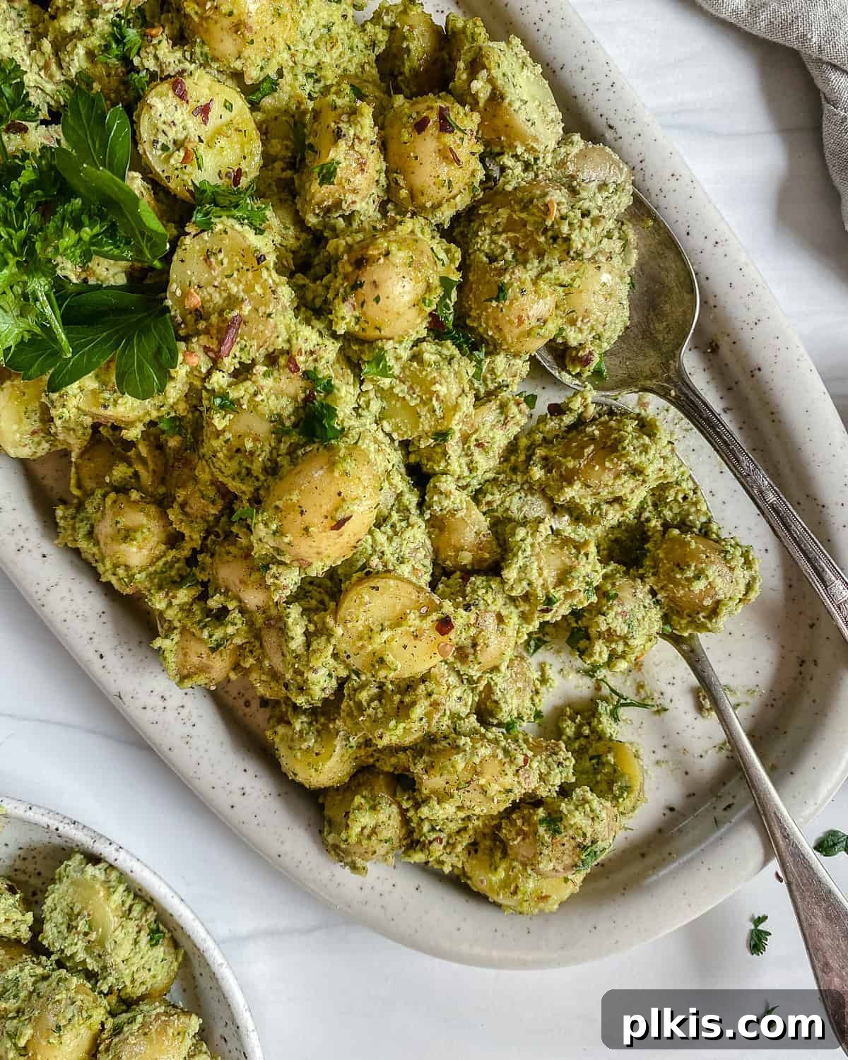 Fresh Parsley Potatoes 2 Completed Almond Parsley Potatoes served in a white baking dish, presented against a clean white background, highlighting the vibrant green parsley and golden brown almonds.