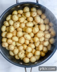 Fresh Parsley Potatoes 4 Process image showing baby potatoes being cooked in a black pot on a stovetop.