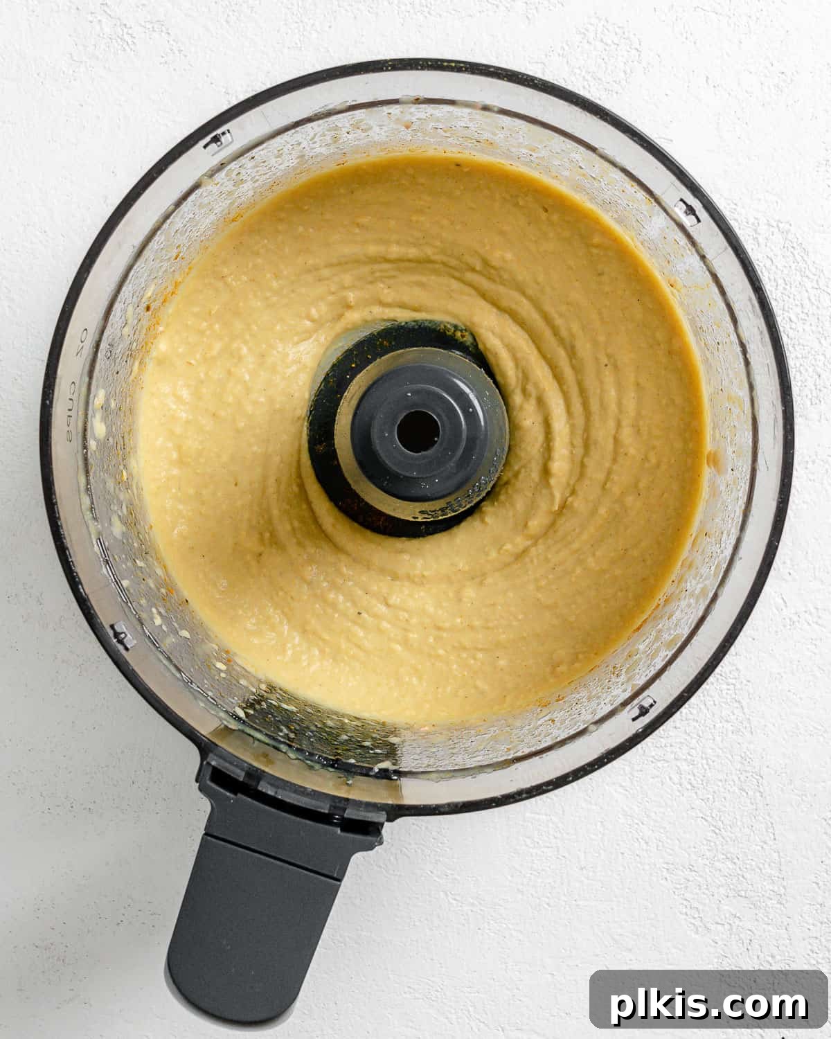 Creamy Vegan Curried White Bean Dip 6 Process shot of the curried white bean dip being blended in a food processor, showing its creamy texture forming.