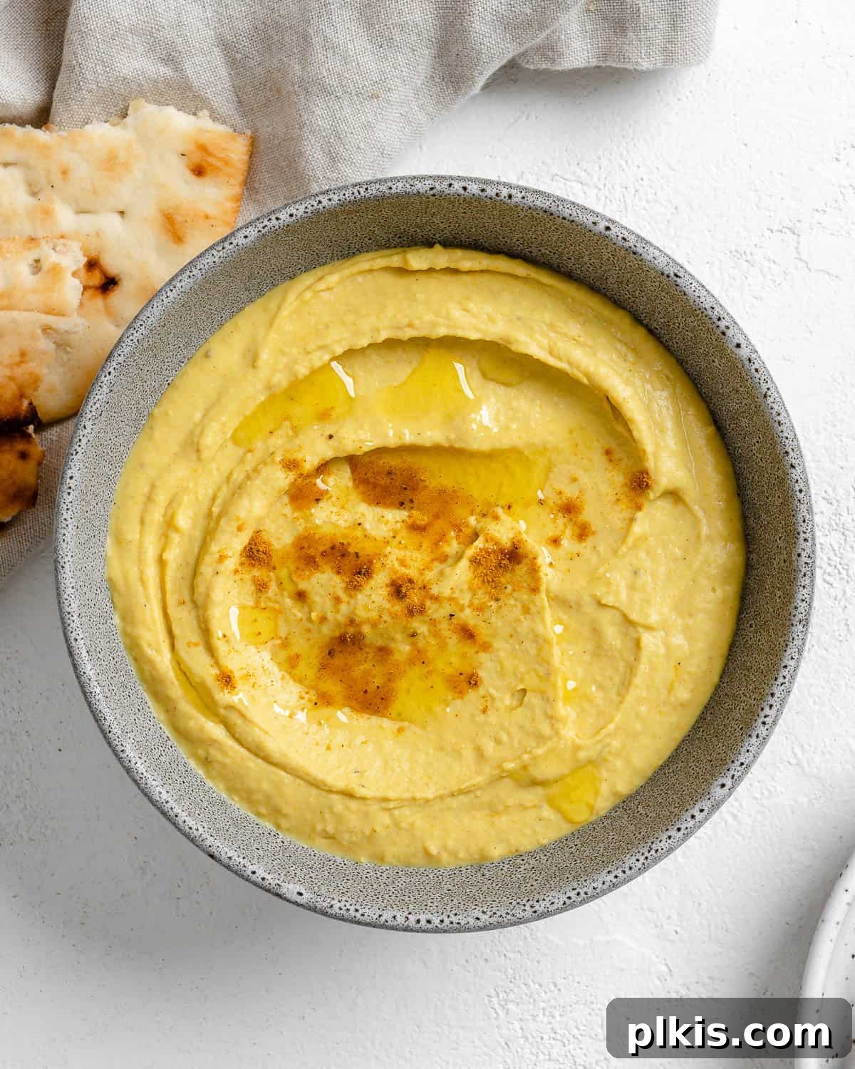Creamy Vegan Curried White Bean Dip 8 The completed Curried White Bean Dip presented beautifully in a grey bowl, garnished and served with fresh bread on a white background.