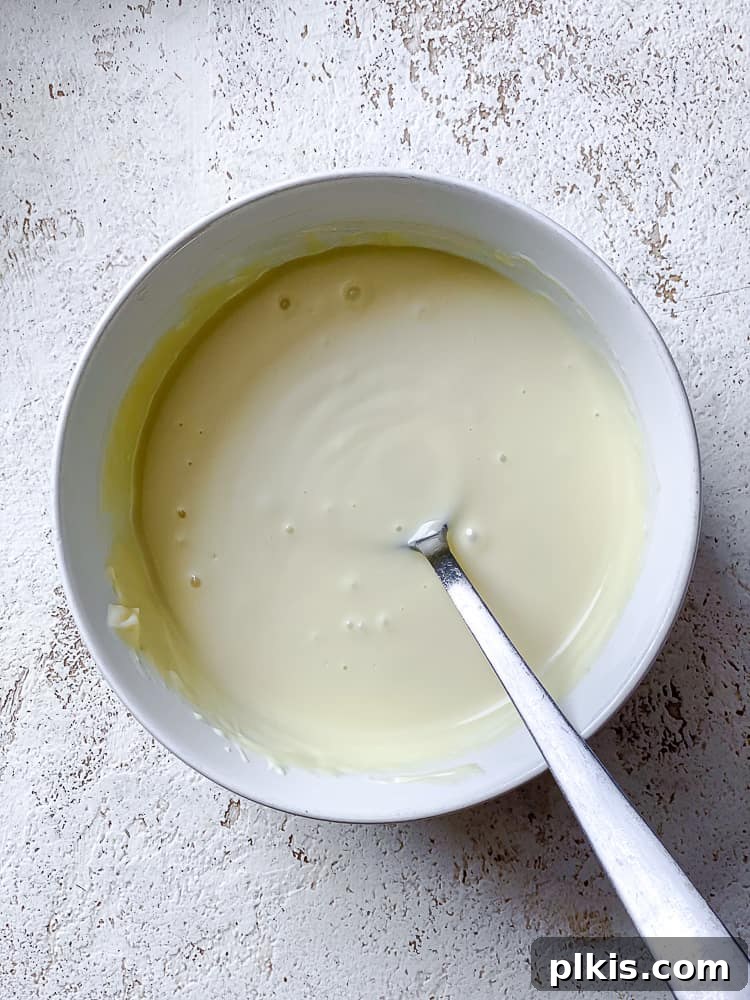 Process shot showing melted vegan white chocolate in a glass bowl, smooth and ready to pour.
