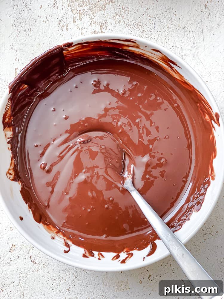 Process shot showing melted vegan dark chocolate in a glass bowl, rich and glossy.
