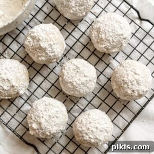 A festive image of perfectly baked and powdered vegan snowball cookies on a cooling rack