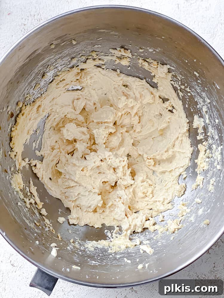 Flavorful Snowball Delights 4 Close-up process shot showing wet ingredients, vegan butter, vanilla, and powdered sugar, being creamed together in a mixing bowl