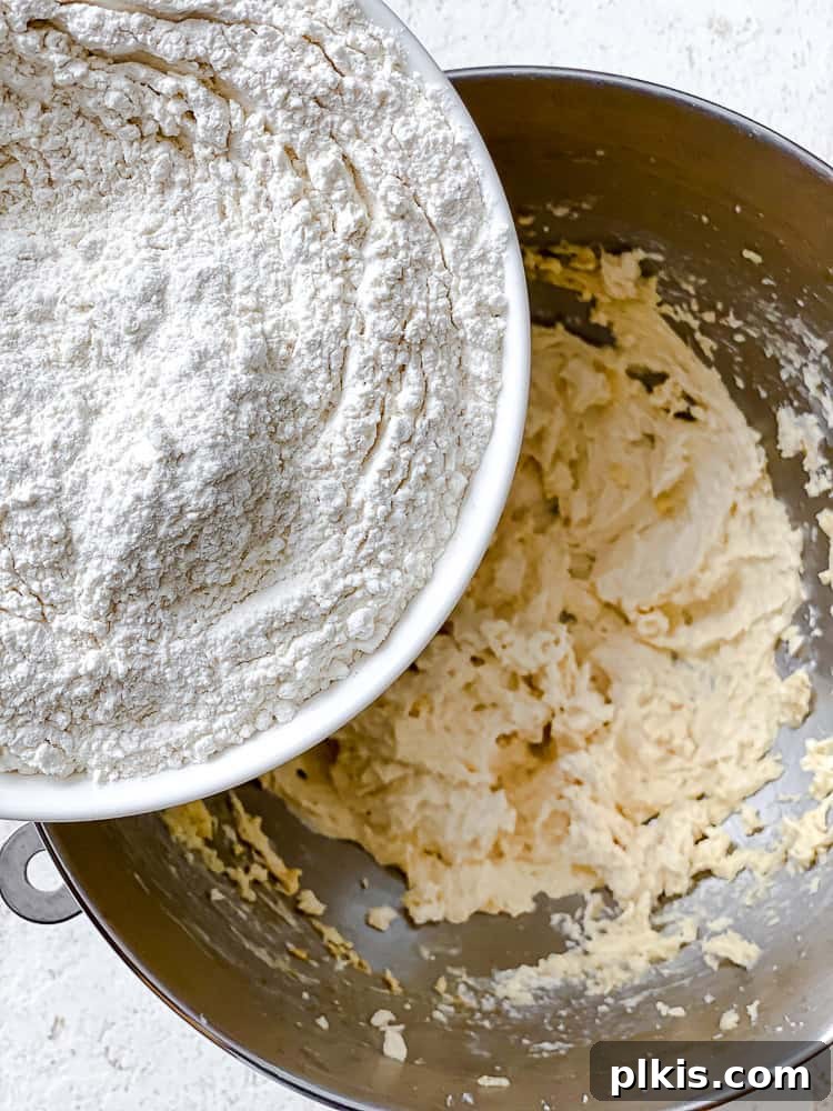Flavorful Snowball Delights 5 Process shot of dry ingredients, flour and salt, being added to the creamed wet ingredients in a bowl