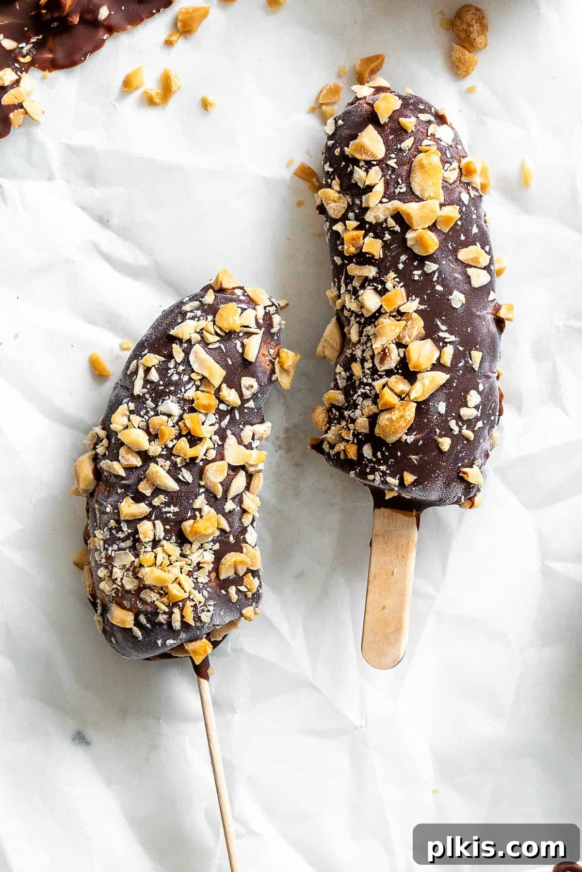 Peanut Butter Chocolate Banana Delights 7 Beautifully completed Peanut Butter and Chocolate Covered Bananas garnished with chopped nuts, presented on a white surface.
