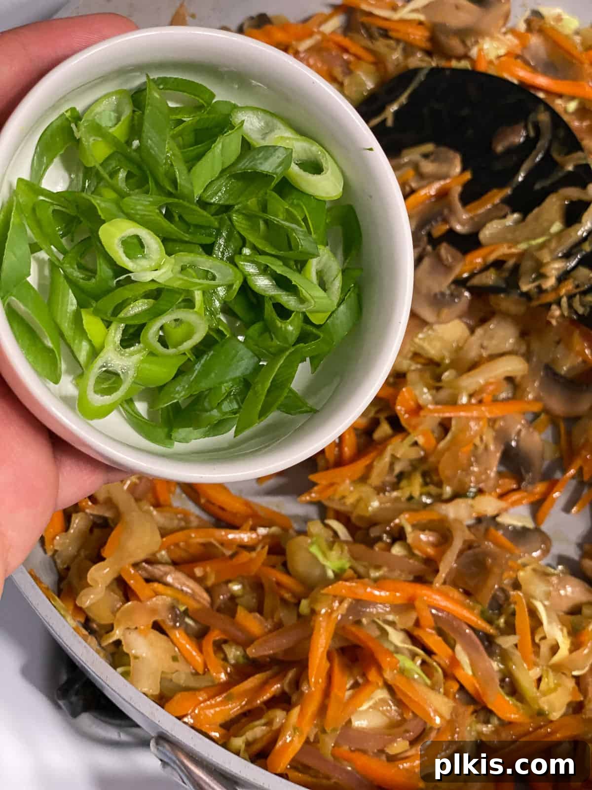 Vibrant Moo Shu Medley 13 A process shot of fresh scallions being stirred into the finished Moo Shu Vegetable, adding a final touch of color and fresh flavor.