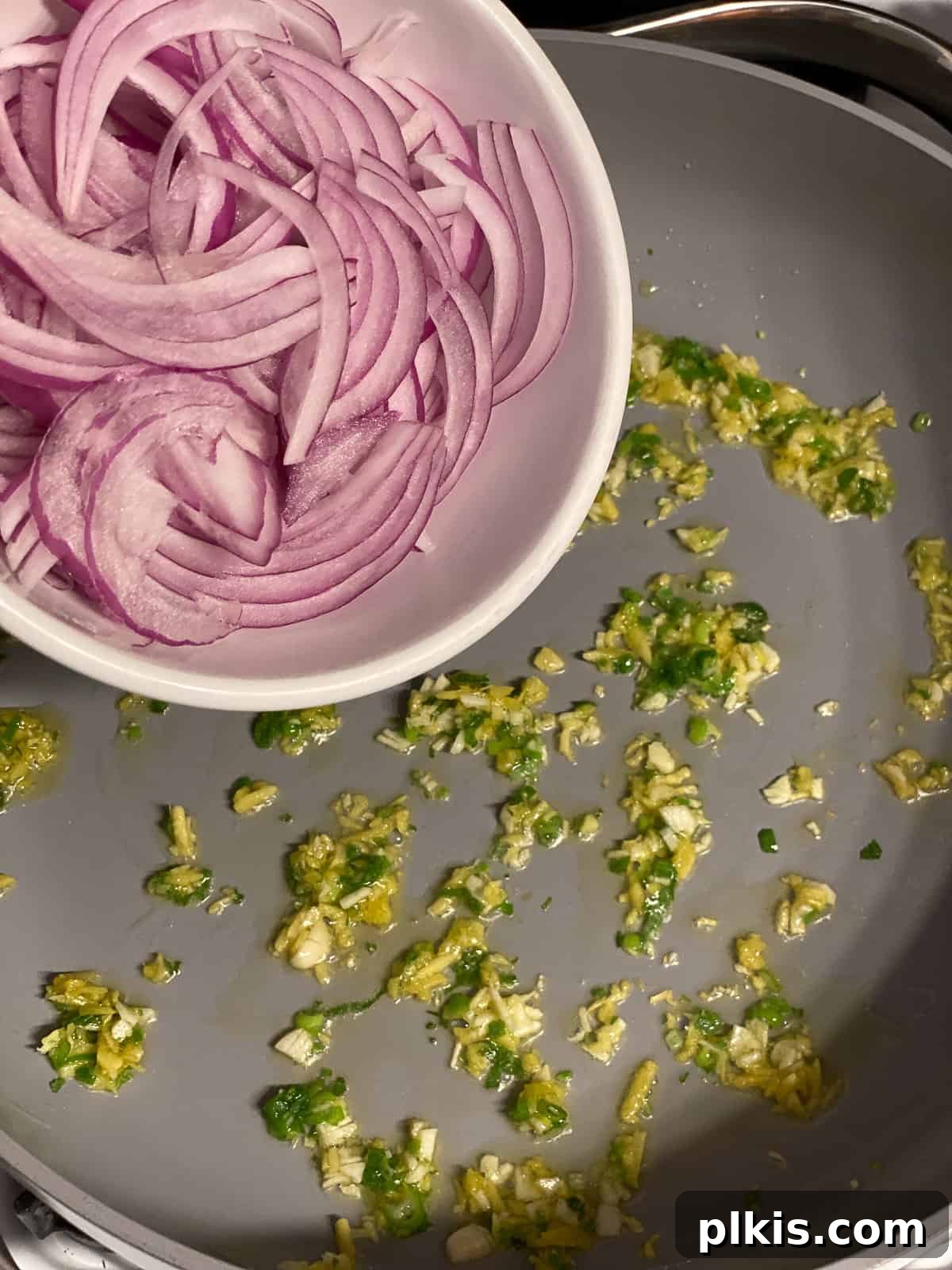 Vibrant Moo Shu Medley 6 A process shot demonstrating thinly sliced onions being added to the hot pan, a key step in building the flavor base for Moo Shu Vegetable.