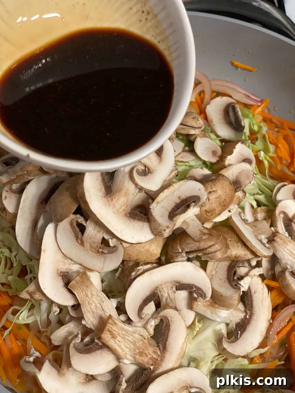 Vibrant Moo Shu Medley 10 A process shot showing the soy sauce mixture being poured over the vegetables in the pan, initiating the saucing stage for Moo Shu Vegetable.