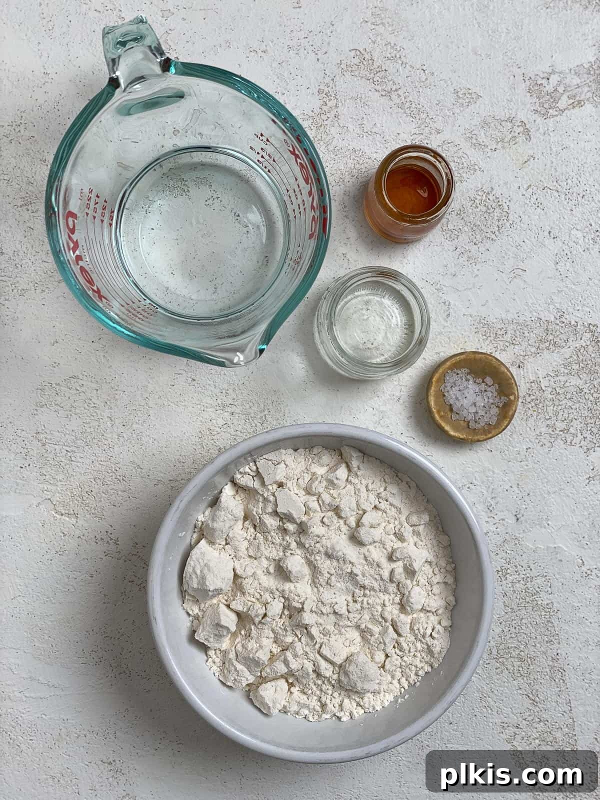 Delicate Chinese Wraps 3 All the necessary ingredients for Mandarin Pancakes laid out on a white surface: all-purpose flour, salt, boiling water, cold water, and sesame oil.