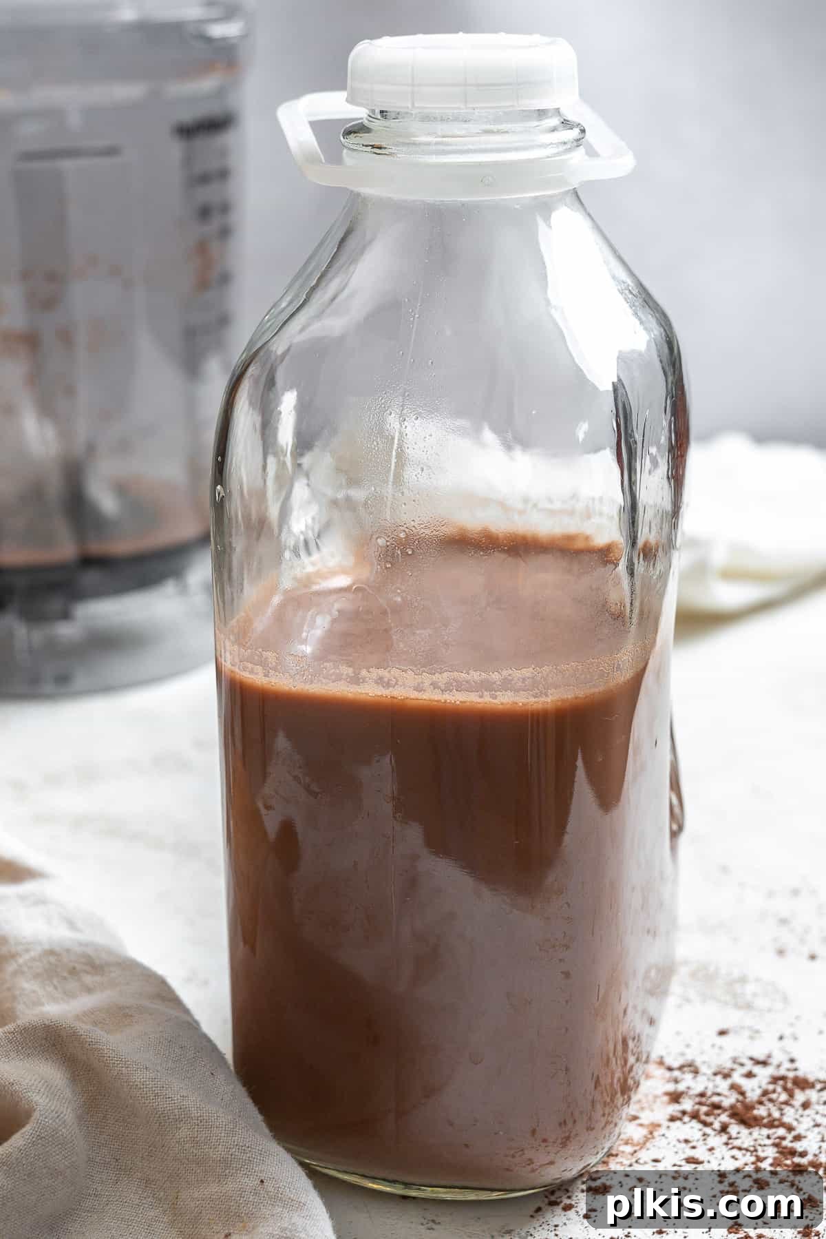 A glass jug filled with freshly made Chocolate Oat Milk, ready for storage in the refrigerator.