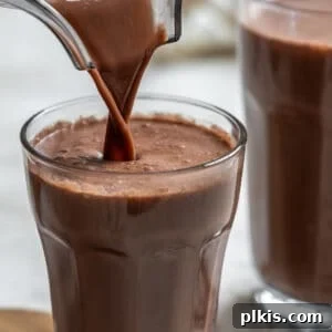 Homemade Chocolate Oat Milk being poured into a glass