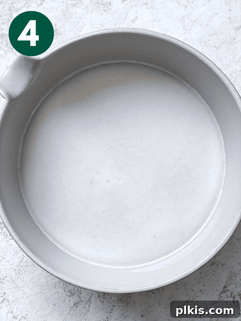 Process shot showing strained oat milk collected in a bowl, ready for the next step.