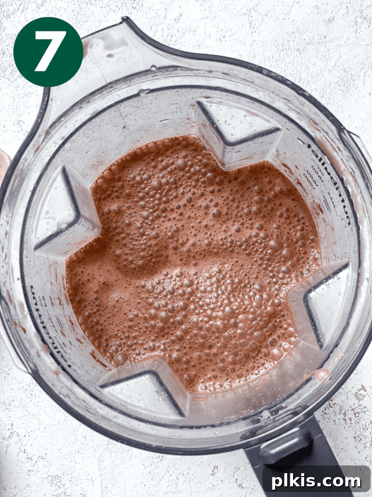 Process shot showing the chocolate oat milk fully blended and ready in the blender.