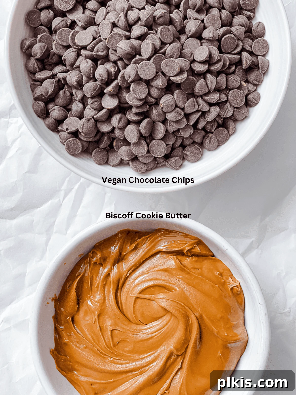 The two key ingredients for Easy Biscoff Fudge [2-Ingredient]: vegan chocolate chips and a jar of smooth Biscoff cookie butter, displayed on a white surface.