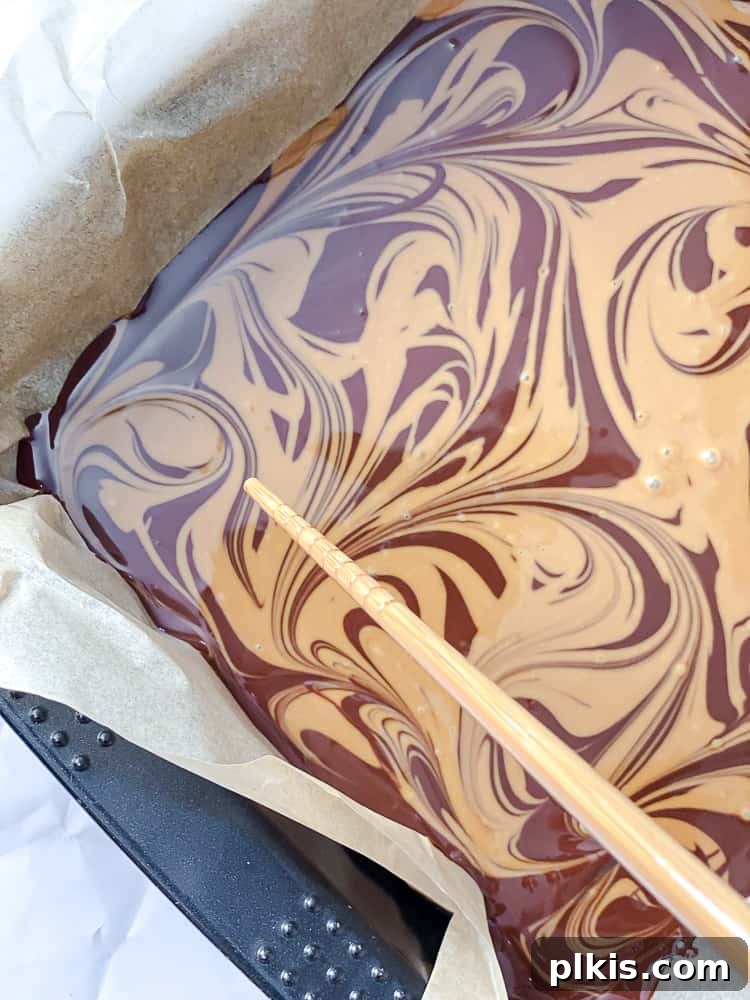 Two-Ingredient Biscoff Fudge Bliss 6 Process shot of swirling the melted Biscoff cookie butter into the chocolate Biscoff fudge mixture in the prepared baking pan.