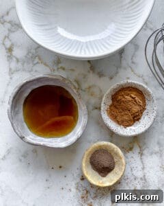 Sweet Heat Cinnamon Almonds 4 Ingredients for cinnamon almonds measured out in individual bowls against a white marble surface.