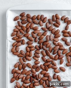 Completed cinnamon almonds against a white surface, showcasing their golden-brown color and crunchy texture.
