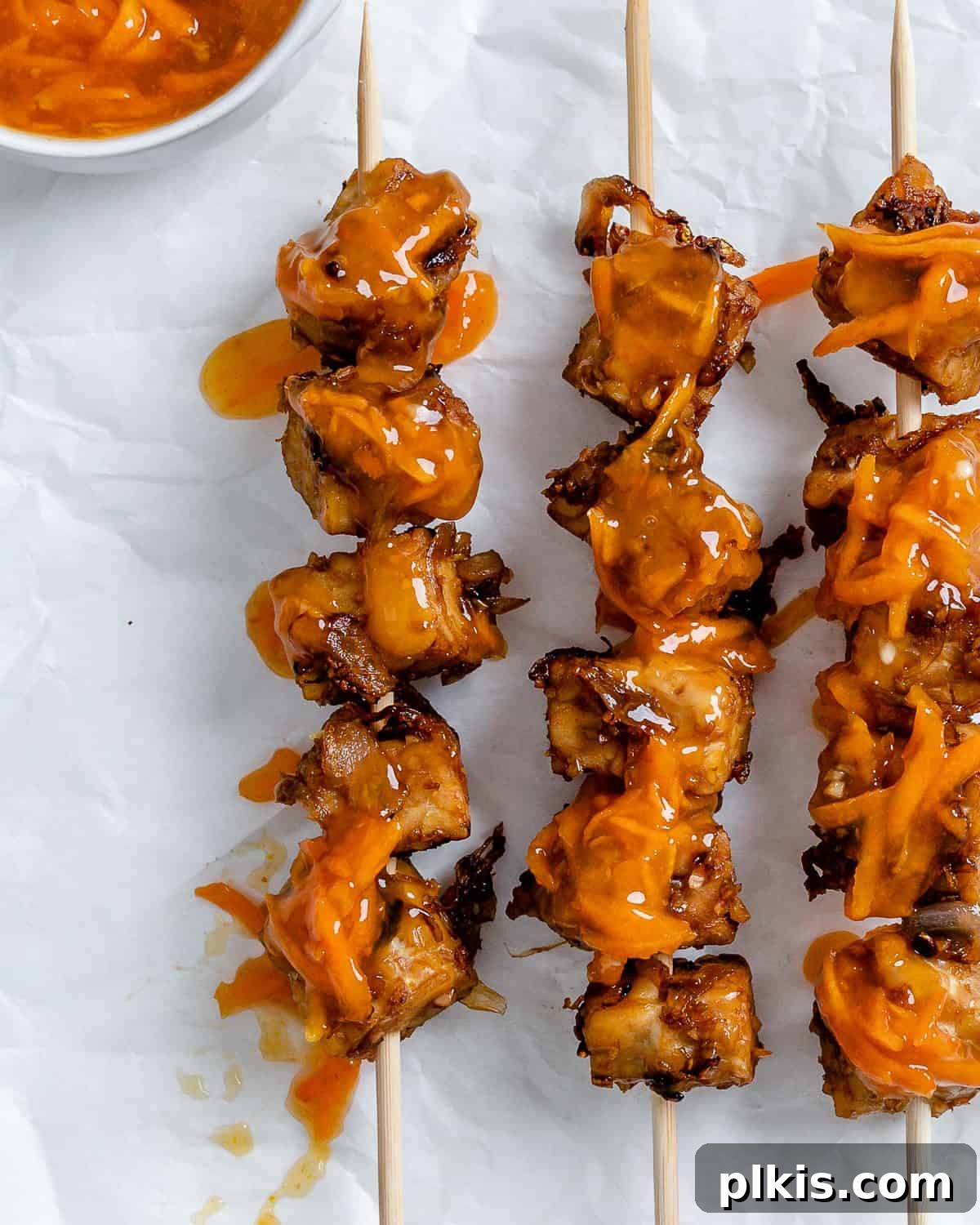 Completed Vegan Kabobs with Marinated Tempeh glistening with orange glaze on a white surface, ready to be served.