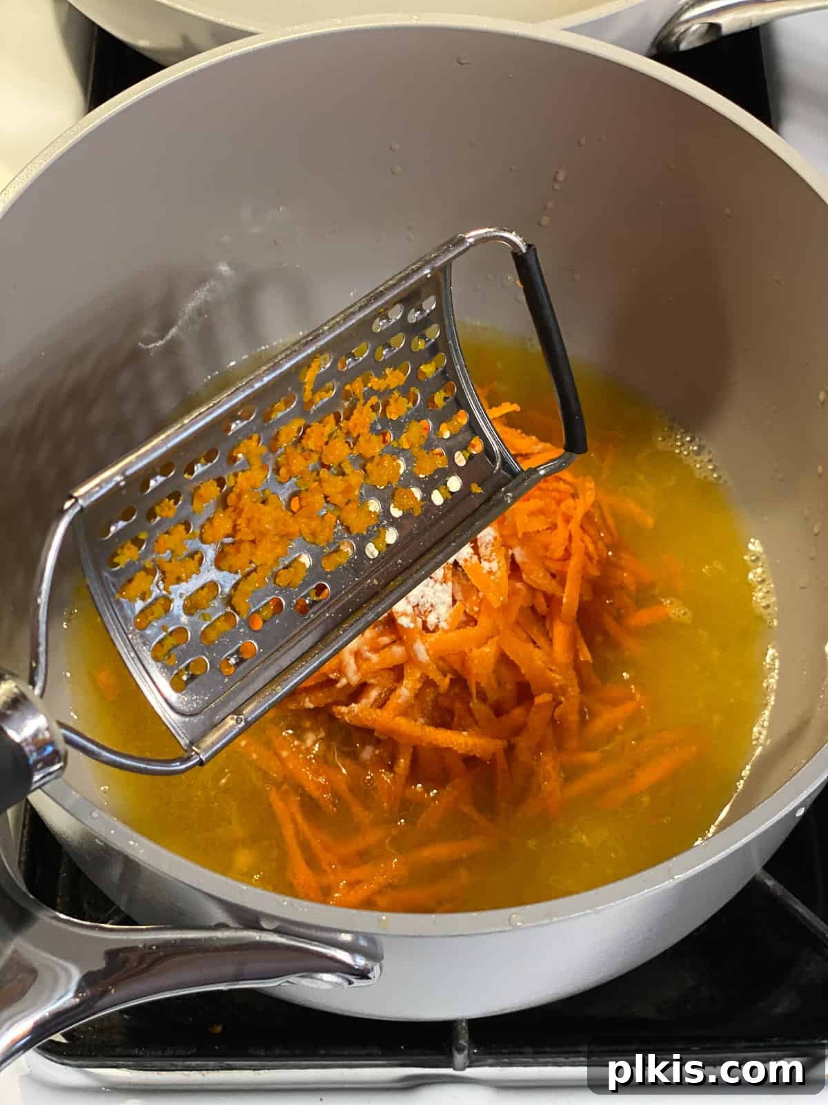 Process shot of grating carrots directly into the pot for the orange glaze.