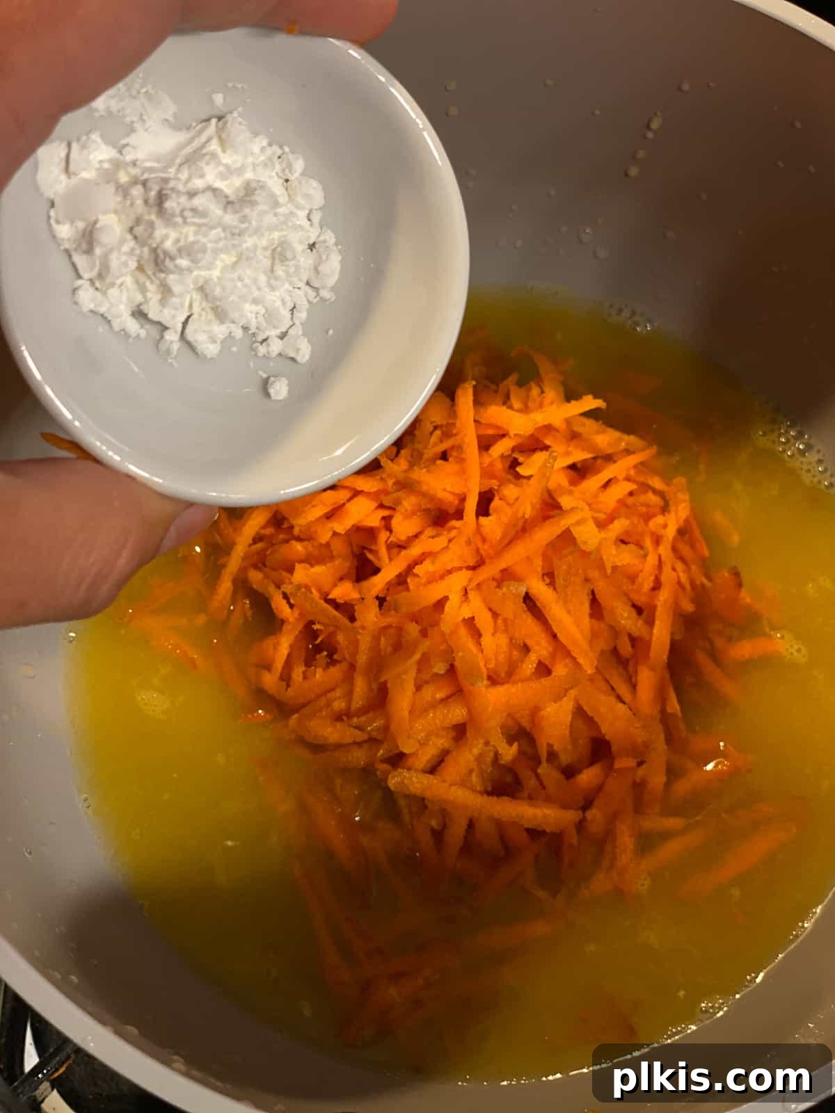 Process shot of adding cornstarch to the glaze mixture in a pot for thickening.