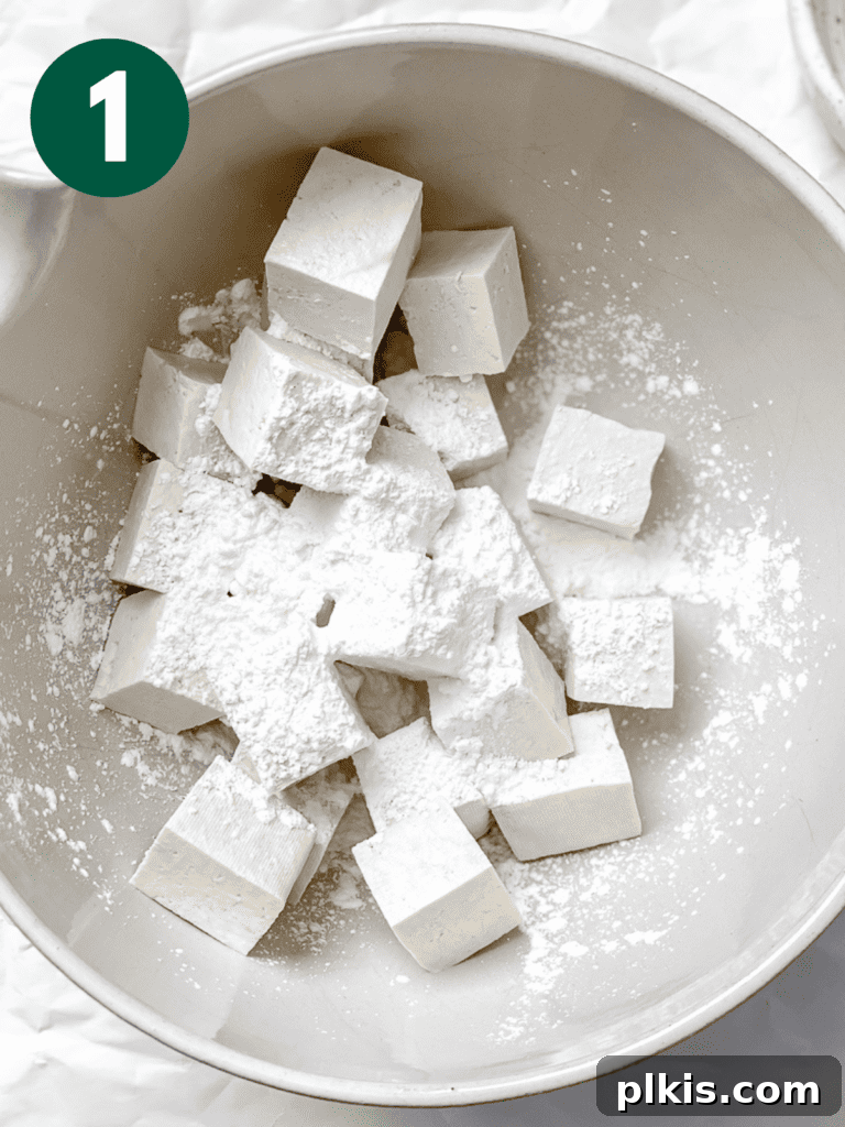 Golden Sweet and Sour Tofu 4 Process shot showing tofu being mixed with cornstarch in a bowl, ensuring an even coating for maximum crispiness.