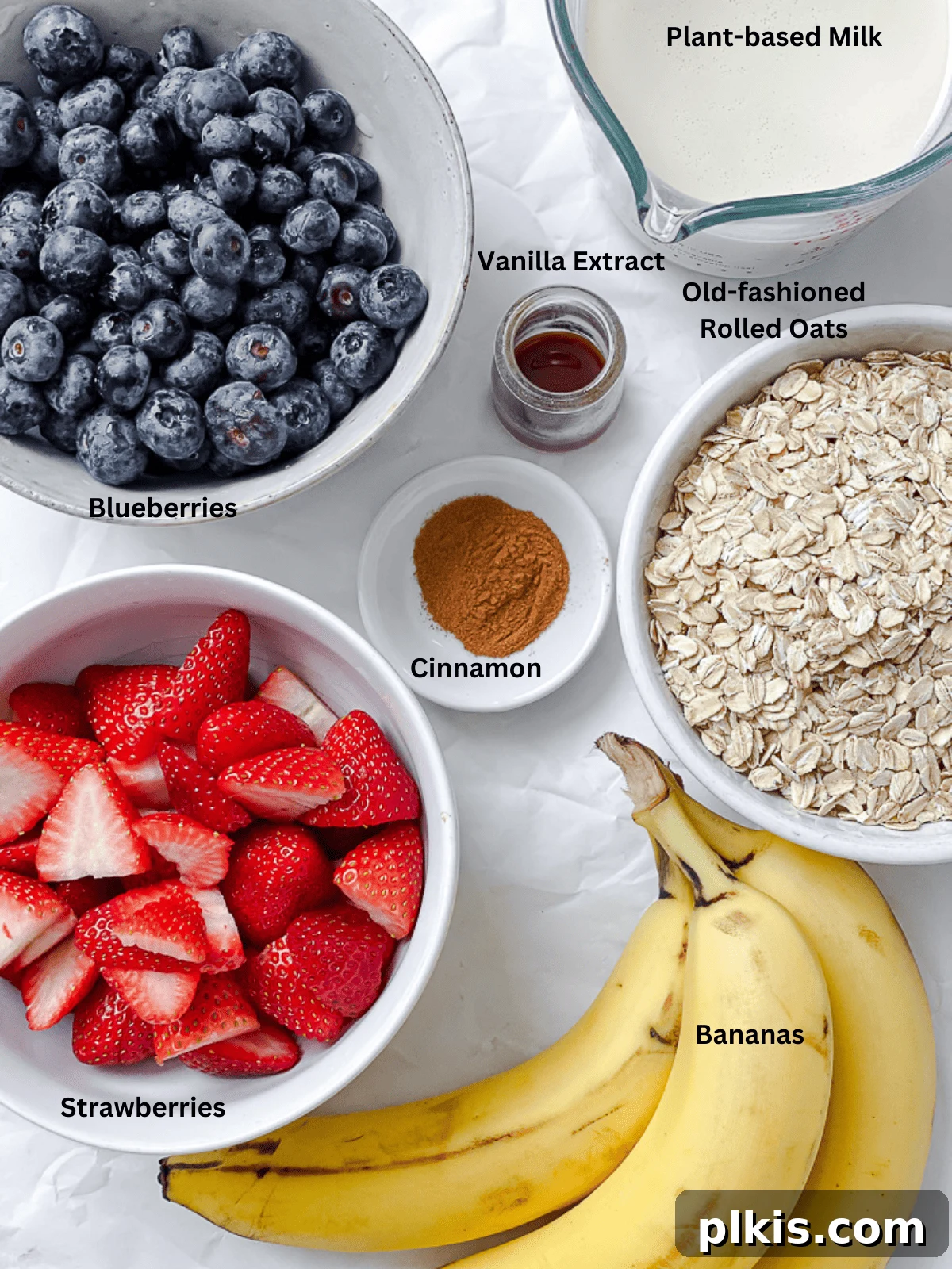 Vegan Berry Baked Oatmeal 3 Ingredients for Vegan Baked Oatmeal with Mixed Berries measured out on a white surface.