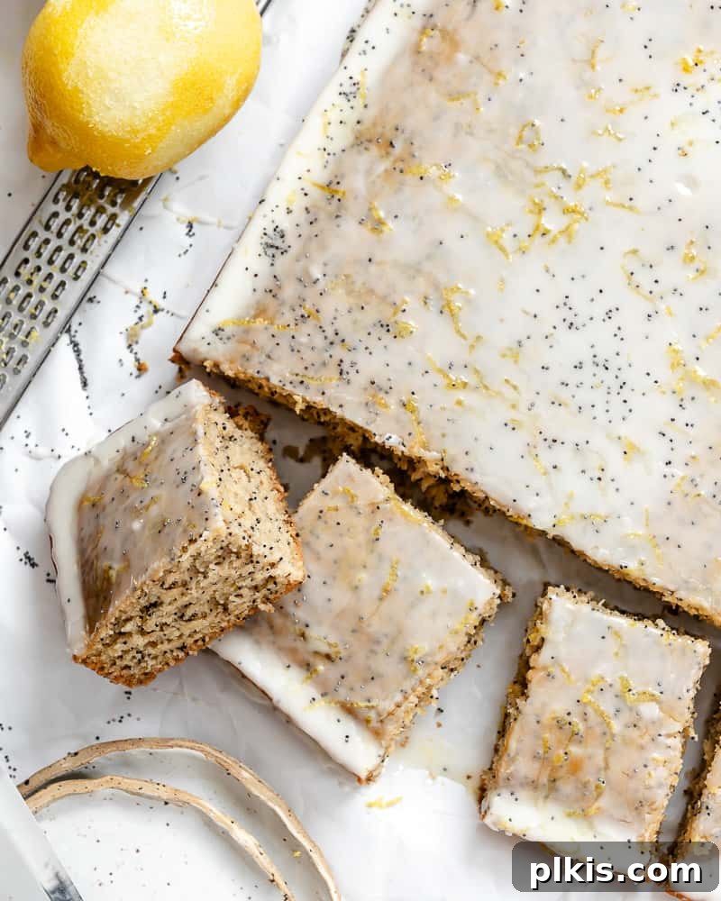 Zesty Lemon Poppy Seed Cake 2 An inviting overhead view of a beautifully sliced vegan lemon poppy seed cake, garnished with lemon zest and poppy seeds.