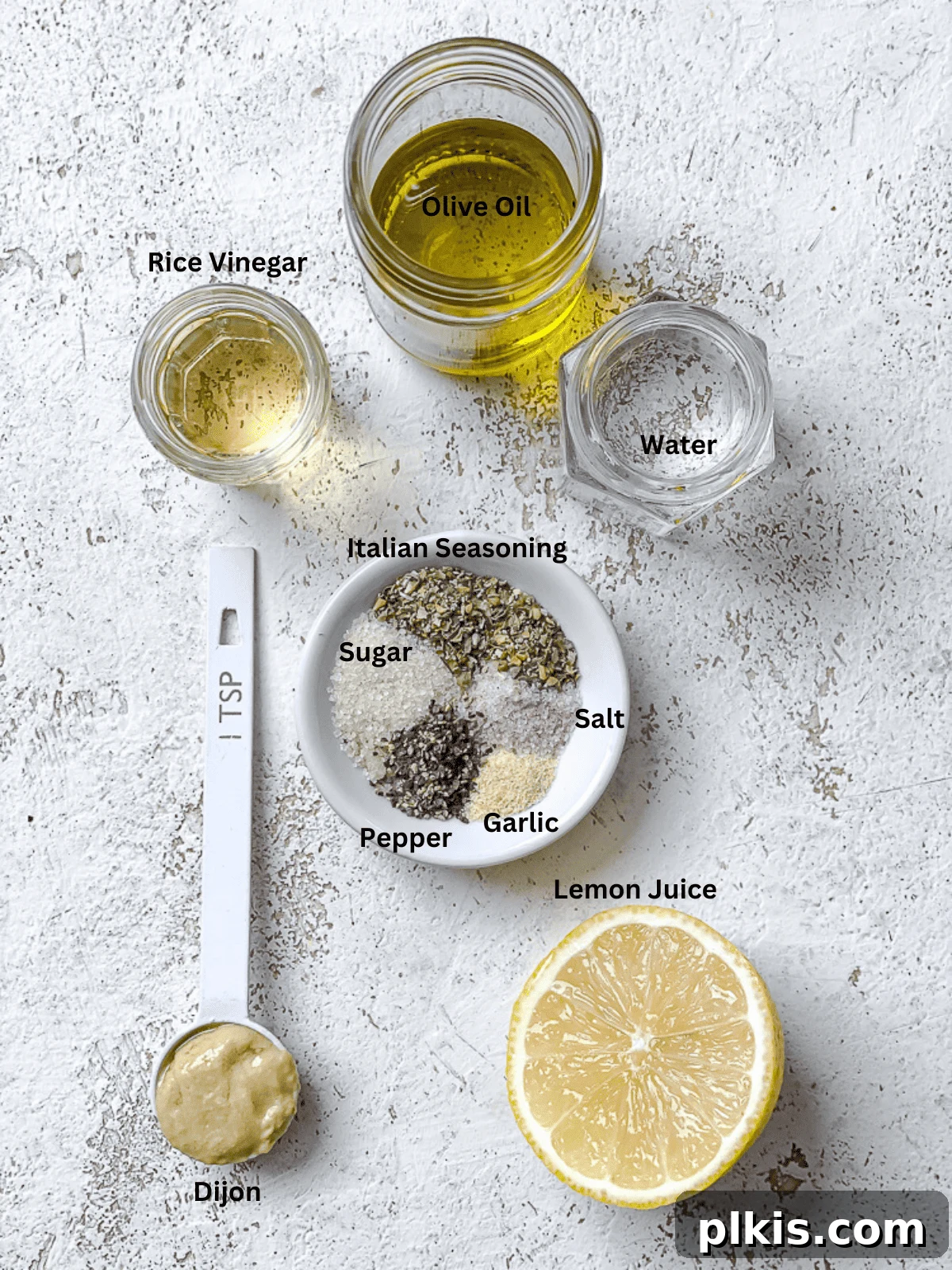3-Minute Plant-Based Italian Dressing 3 All the individual ingredients for a simple homemade vegan Italian dressing laid out on a white surface, showing fresh lemon, olive oil, and various spices.