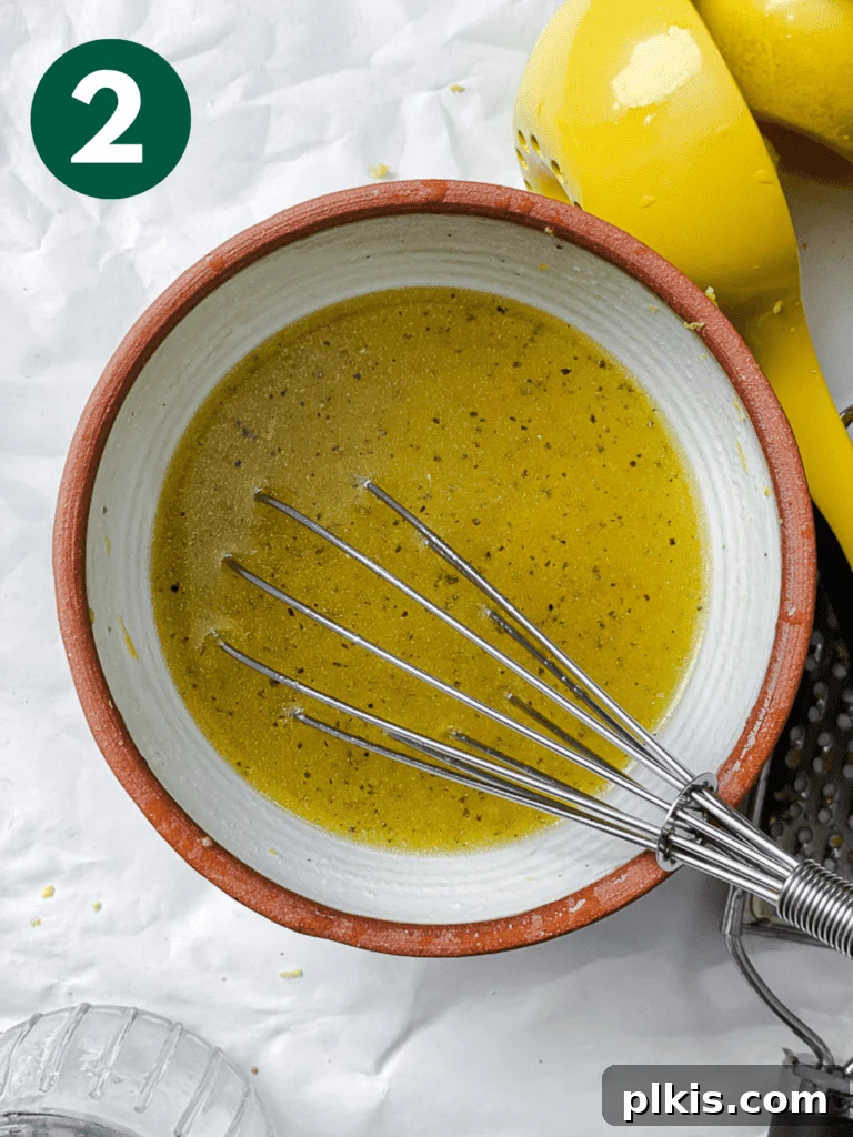 Power-Packed Kale Quinoa Salad 5 A process shot depicting the dressing ingredients being thoroughly whisked together in a bowl, creating a smooth and emulsified mixture.