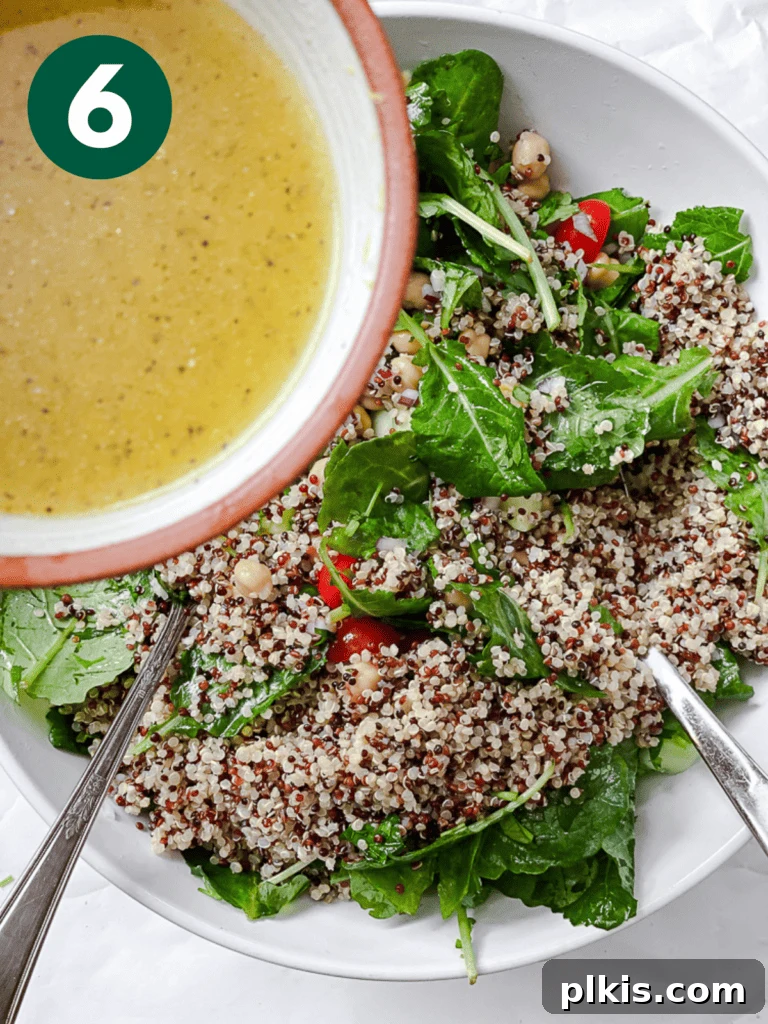 Power-Packed Kale Quinoa Salad 9 A process shot capturing the moment dressing is being drizzled over a bowl of fresh greens and salad ingredients, ready for a final toss.