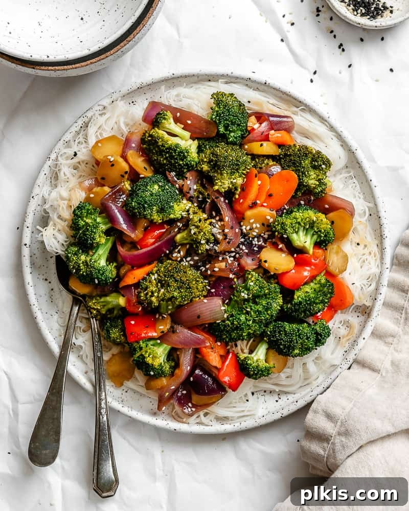 Completed Easy Garlic Broccoli Stir-Fry on a white plate, garnished with sesame seeds and green onions.