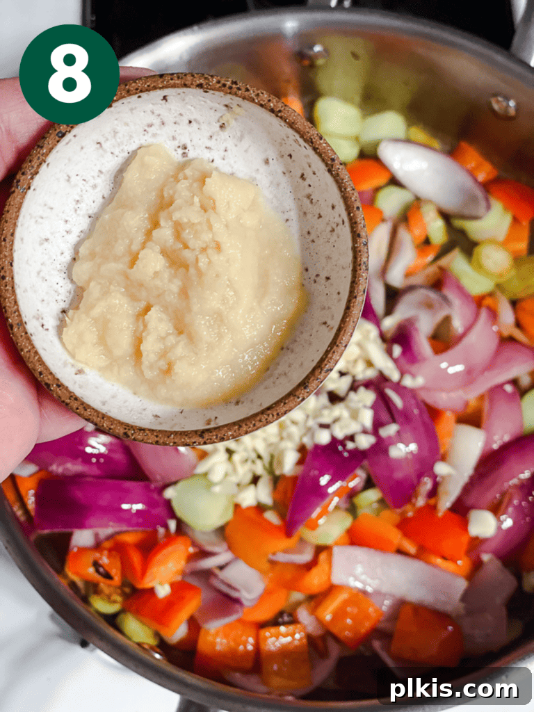Process shot of adding more ingredients to the stir-fry pan.