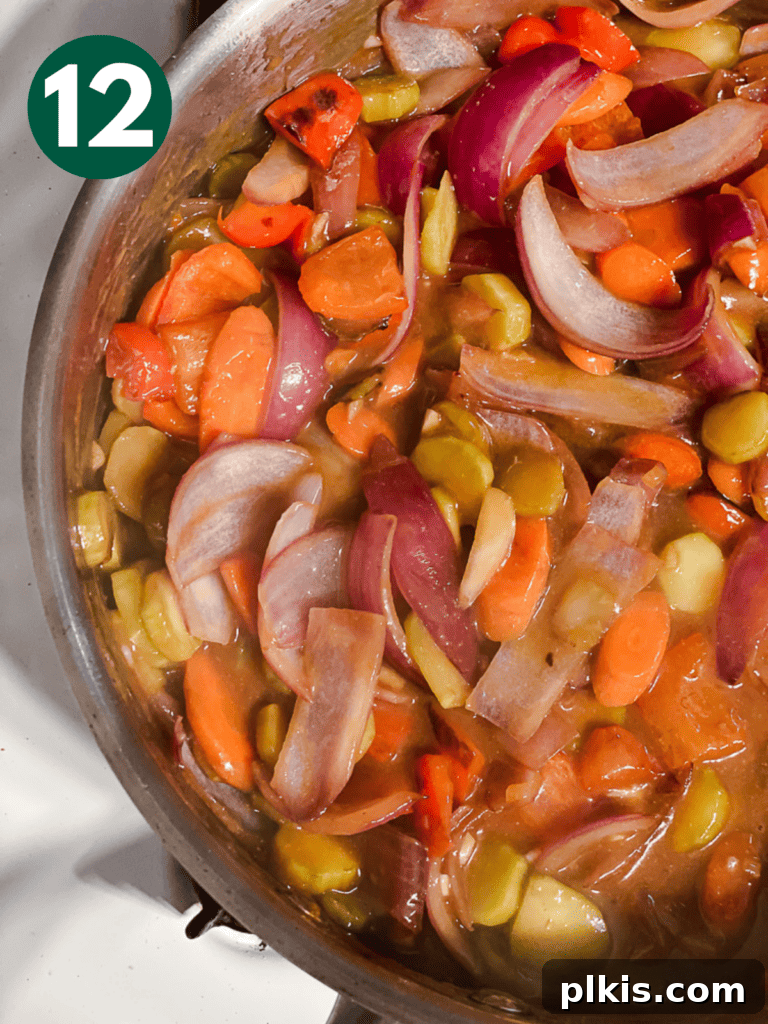 Process shot of the sauce being mixed into the vegetables, starting to thicken.