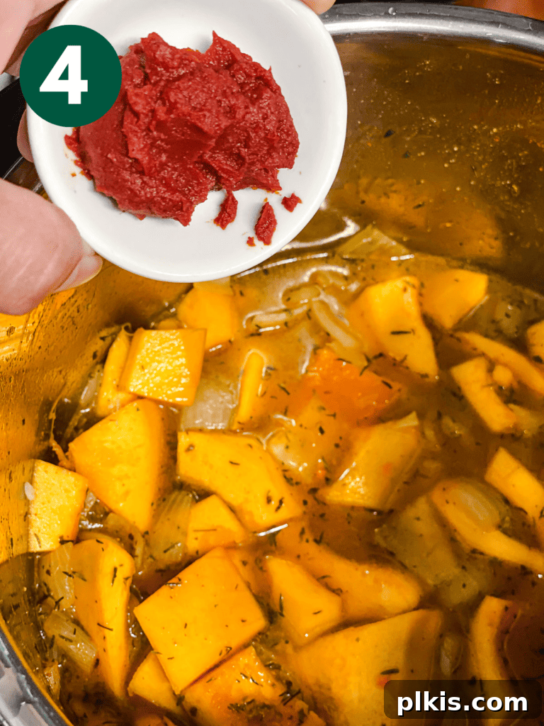 Cozy Slow Cooker Spiced Pumpkin Bisque 7 process shot showing adding tomatoes to pot