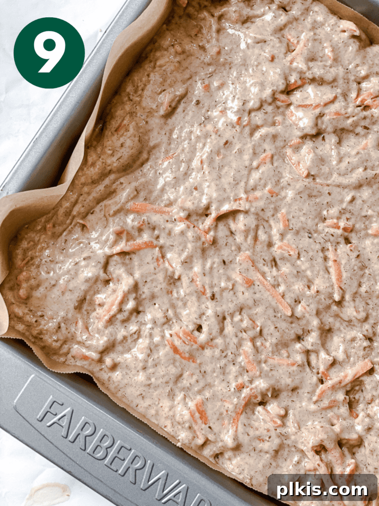A process shot displaying the completed cake batter poured into a parchment-lined baking dish, ready for the oven.