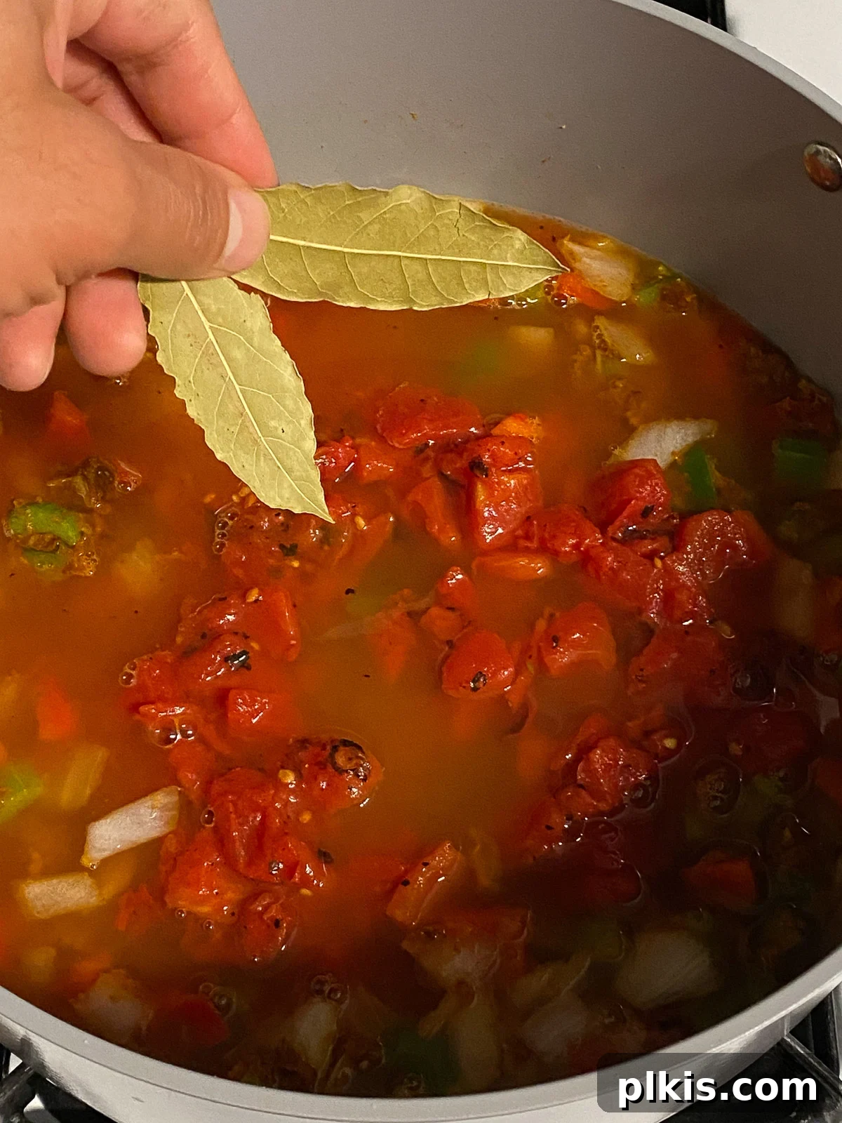 Hearty Plant-Based Gumbo 11 process shot of bay leaves being added to the gumbo mixture in the pot
