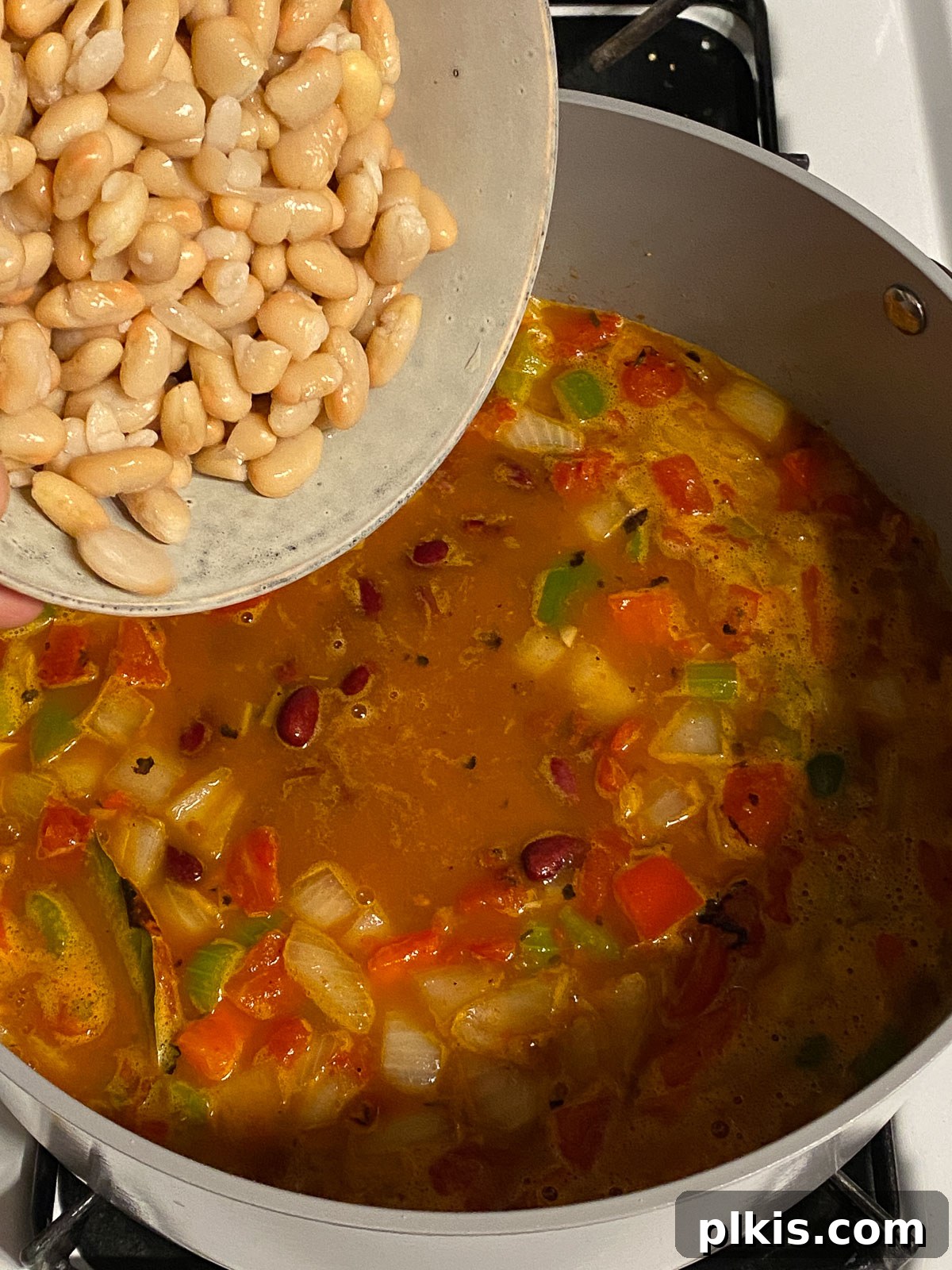 Hearty Plant-Based Gumbo 13 process shot of white beans being added to the gumbo in the pot