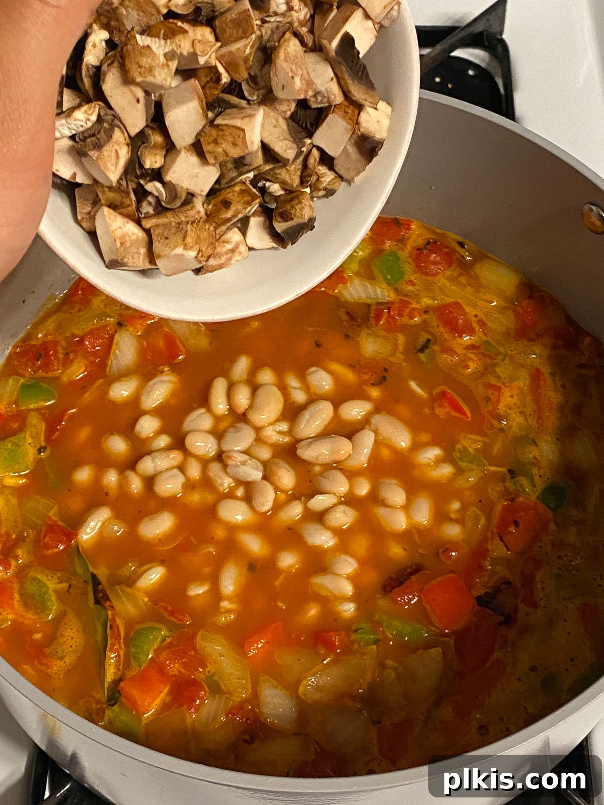 Hearty Plant-Based Gumbo 14 process shot of sliced mushrooms being added to the gumbo in the pot