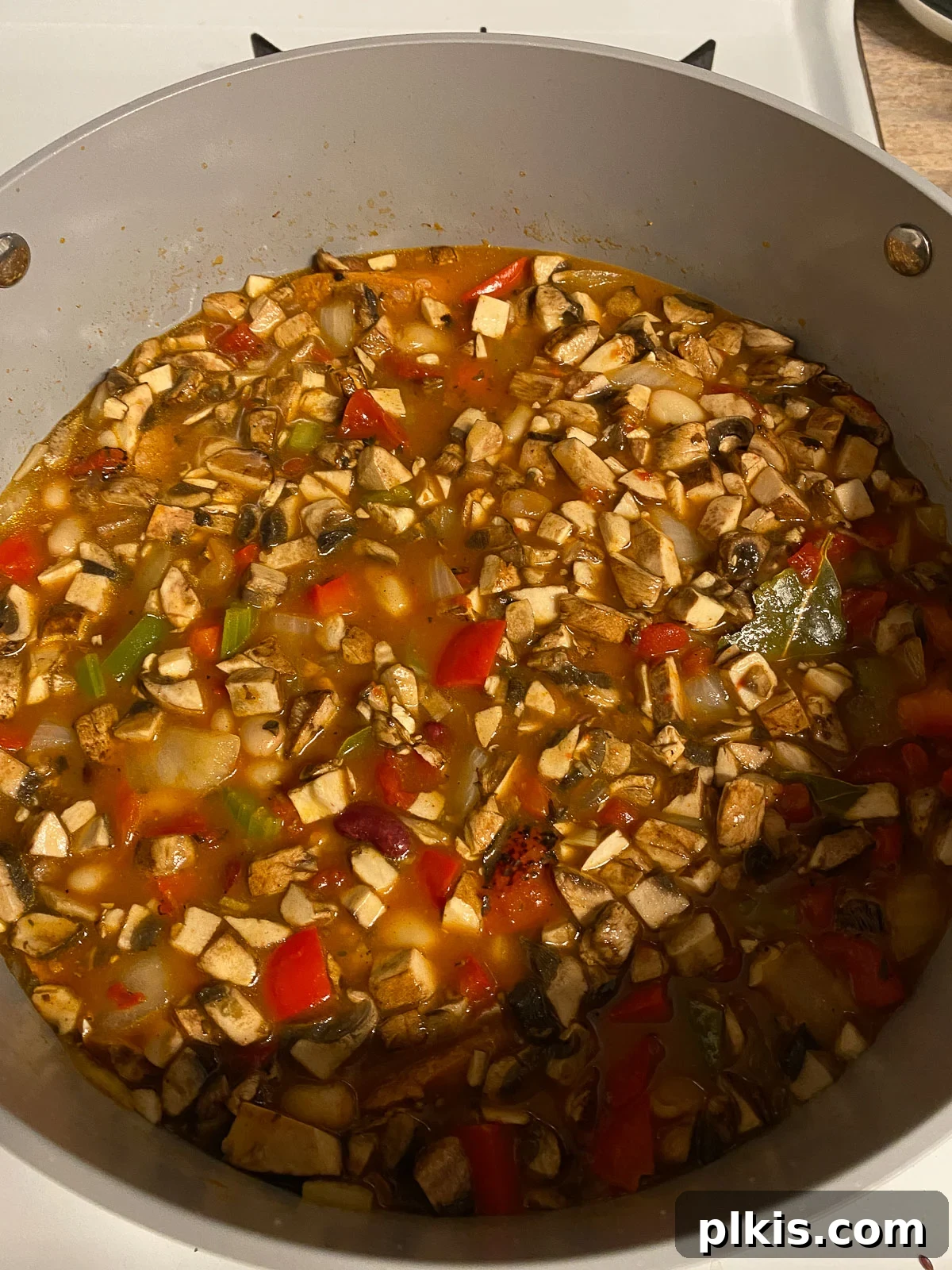 Hearty Plant-Based Gumbo 16 process shot of vegan gumbo simmering gently in the pan, covered