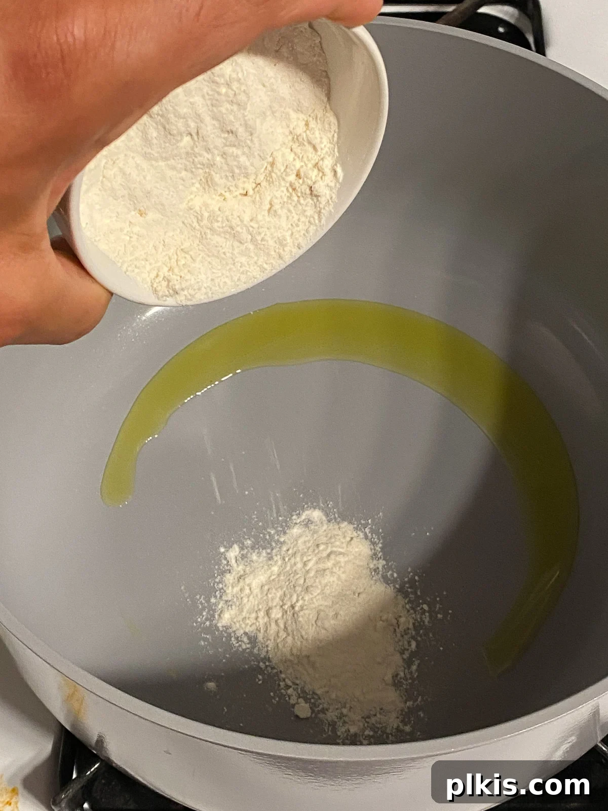 Hearty Plant-Based Gumbo 5 process shot of flour being poured into pan with hot oil, beginning the roux
